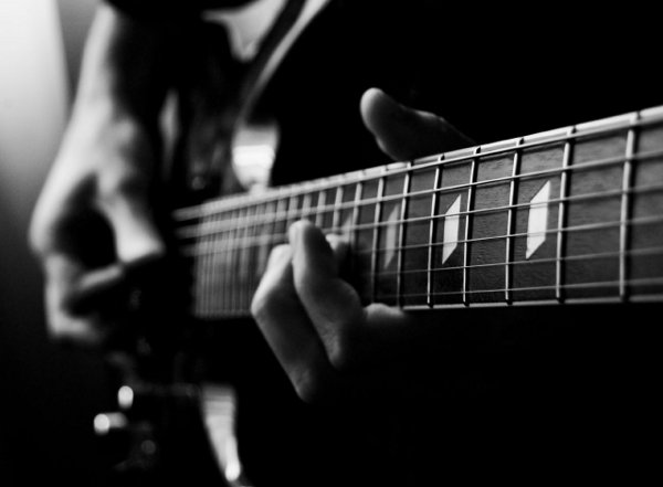 black and white picture of guitar fretboard - looks like someone in their bedroom practicing scales, etc